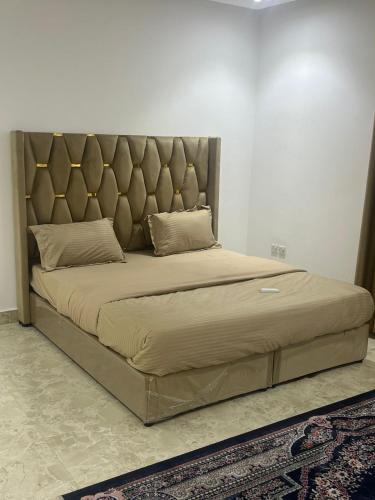 a large bed with a padded headboard in a bedroom at شقق الشموخ in Dammam