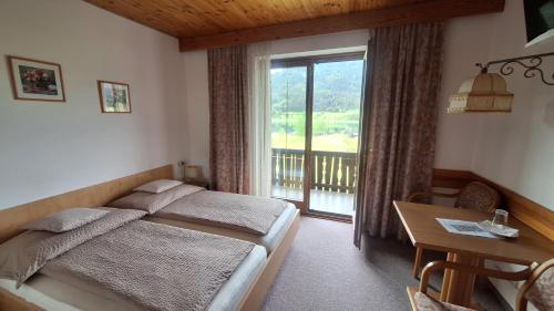 a bedroom with a bed and a table and a window at Haus Alpenfriede in Weissensee