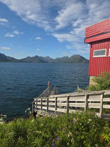 a red house with a fence next to a body of water at Grønningbrygga in Grønning