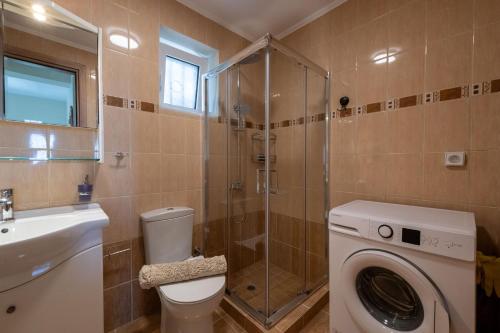 a bathroom with a toilet and a shower and a washing machine at Anima Horizon - Thea apartment in Elaiófiton
