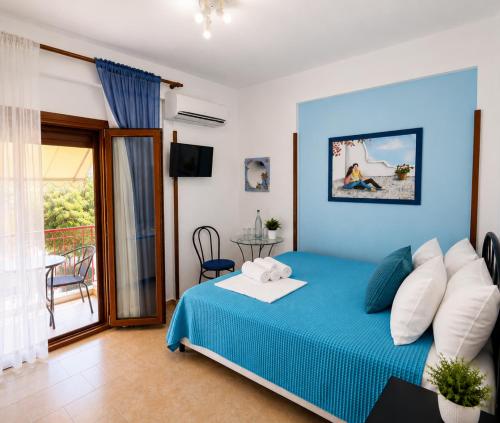 a bedroom with a blue bed and a balcony at Gallery in Ammouliani