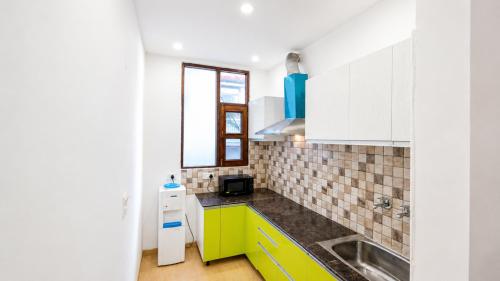 a kitchen with yellow and white cabinets and a sink at Holiday In Homestay in Shimla