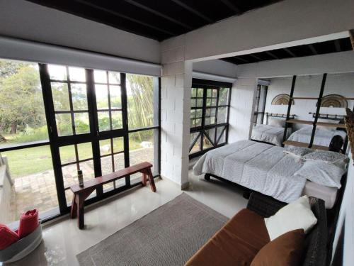 a bedroom with a bed and a couch and windows at Cabaña MACA in Darién