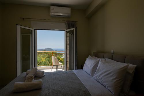 a bedroom with a bed with a view of a balcony at Anima Horizon - Thea apartment in Elaiófiton