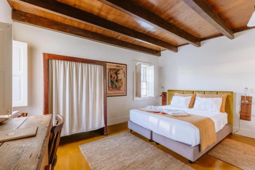 a bedroom with a large white bed and a desk at Galricho Heritage House in Murtosa