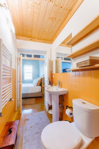 a bathroom with a toilet and a sink and a bed at Galricho Heritage House in Murtosa