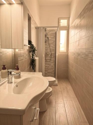a white bathroom with a sink and two toilets at Mimmo Wanderlust in Mazzeo