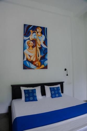 a bedroom with a bed with a painting on the wall at Everdew Kandy Rooms in Kandy