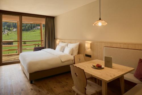 a hotel room with a bed and a table and a window at Hotel Bella Vista in Trafoi