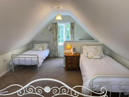 a attic room with two beds and a window at Breach Lodge in Bonvilston