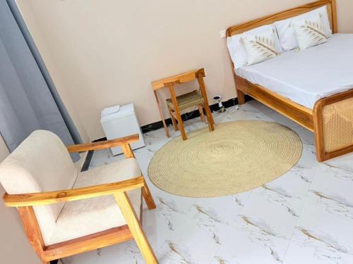a bedroom with a bed and a chair and a table at Rocky Apartment Zanzibar in Zanzibar City