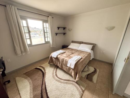 a bedroom with a bed and a window and a rug at Morada Pé de Laranja in Lages