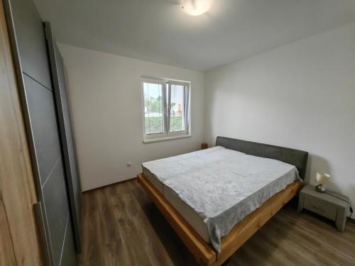 a white bedroom with a bed and a window at Apartment J&D in Dunajská Streda