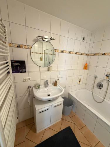 a bathroom with a sink and a tub and a mirror at Modern Living - Tuttlingen in Tuttlingen