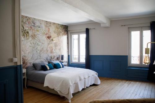 a bedroom with a large bed with blue walls at L' Accointance in Semur-en-Auxois