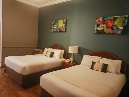 a hotel room with two beds and a painting on the wall at Scala Hotel in Lagos de Moreno