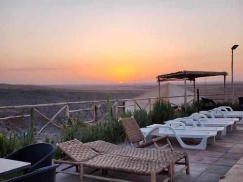 a group of tables and chairs with the sunset in the background at Travel sky morocco camp in El Karia