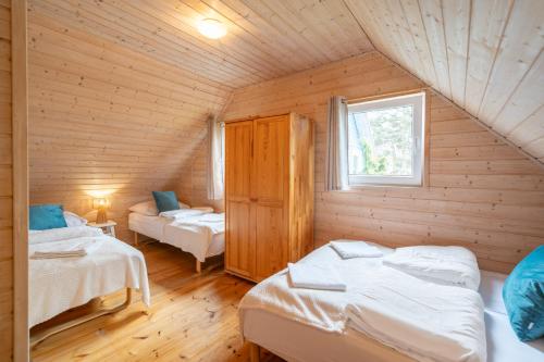 a attic room with two beds and a window at Domki Błękitne Nad Morzem Międzywodzie in Międzywodzie
