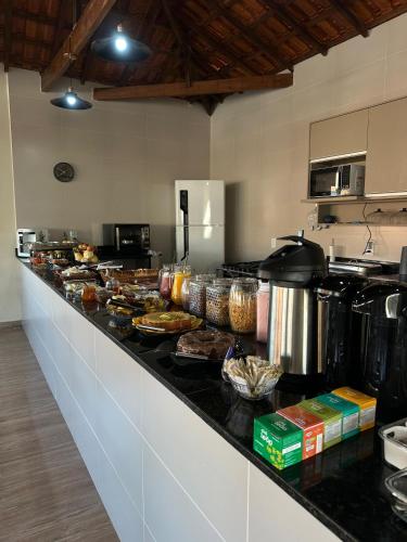 a long counter in a kitchen with alot of food at Suite com cozinha 250m do centro in São Thomé das Letras