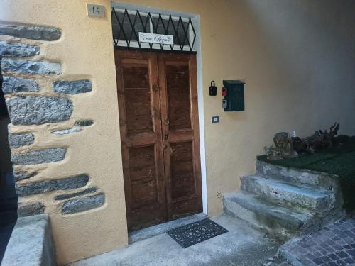 a door to a building with a stone wall and stairs at Casa Regina in Dongo