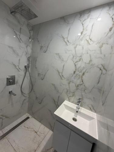 a white marble bathroom with a sink and a shower at Apartment with sauna and fireplace in Viitna