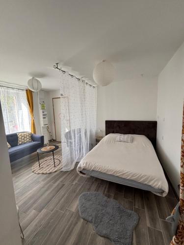a bedroom with a large bed and a blue couch at Appart Résidence Yadah RDC in Granville