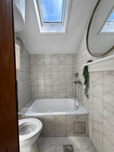 a bathroom with a tub and a toilet and a window at Apartmani MM Trebinje in Trebinje