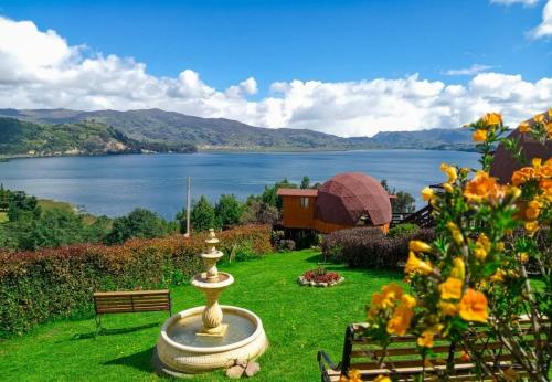 a garden with a fountain and a view of a lake at Domos Lago Muisca Chia in Aquitania