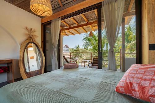 a bedroom with a bed and a large window at Punta Arena Surf Suites in Puerto Escondido