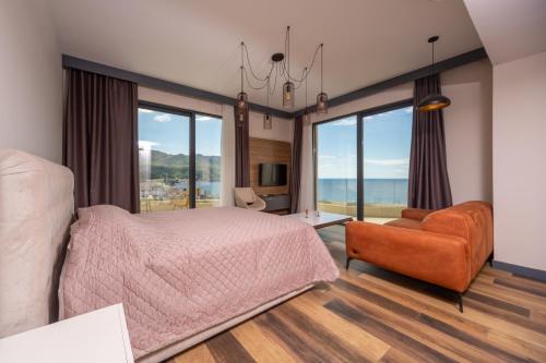 a bedroom with a bed and a chair and large windows at Boreti Panorama Residence in Boreti