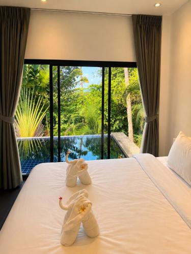 two stuffed elephants sitting on a bed in a bedroom at Villa Ravenala in Chaweng in Ban Ko Khwan