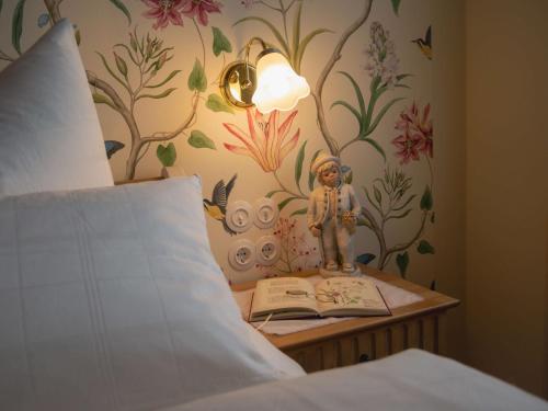 a table with a book and a statue next to a bed at Die Gute Stube in Dobritz