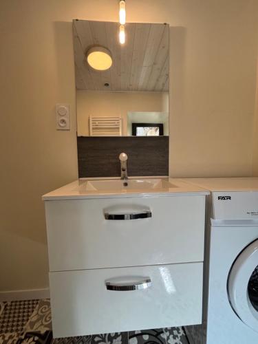 a bathroom with a sink and a washing machine at Escapade en Auvergne - centre historique - 3 personnes in Olliergues