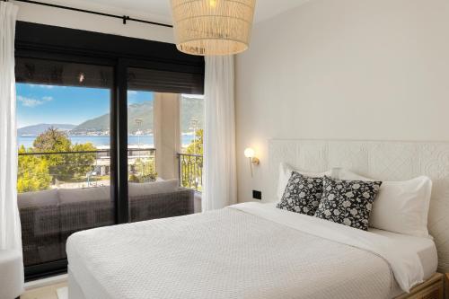 a bedroom with a white bed and a large window at Luxurious Bohemian Residence with Pool in Tivat