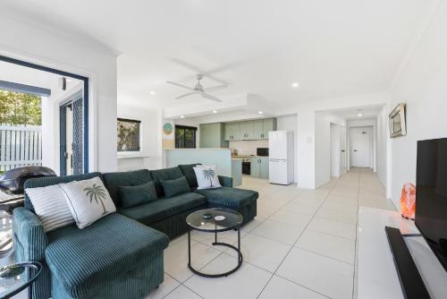 a living room with a green couch and a kitchen at Poolside 2-Bed Apartment Near Coolangatta in Gold Coast