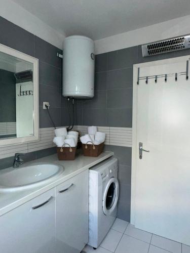 a bathroom with a washing machine and a sink at Apartment Cherry s pogledom na more in Dinjiška