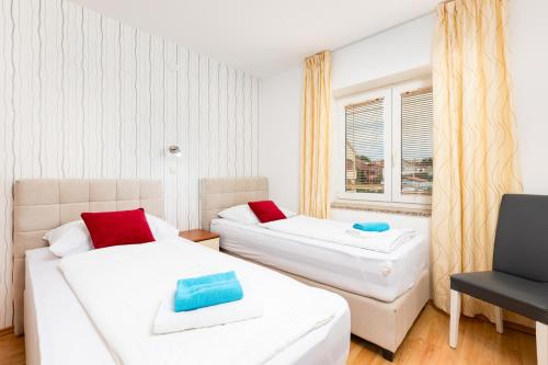 two beds in a room with a window at Apartman Izi Green s pogledom na more in Kornić