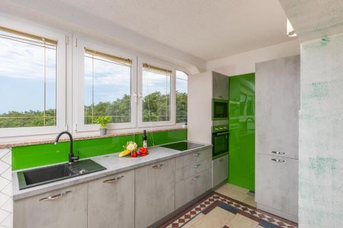 a kitchen with green walls and a sink and windows at Apartman Izi Green s pogledom na more in Kornić