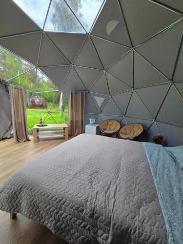a bedroom with a large bed and a large glass wall at Spranču Glempings in Bernāti