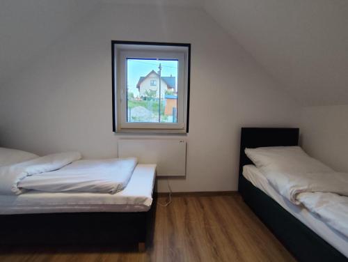 two beds in a room with a window at Osada ŁYSKA in Żywiec