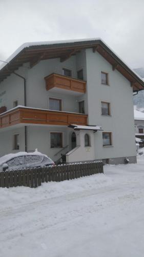 a large white building with a balcony in the snow at Ferienwohnungen Egger in Zell am Ziller