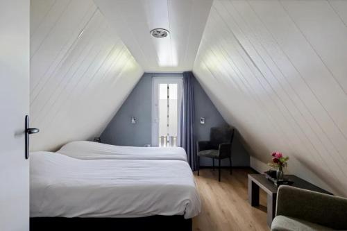 a attic bedroom with two beds and a chair at Vijverzicht de Goudkarper 154 in Gramsbergen