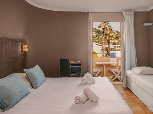 a bedroom with a bed with two towels on it at Hotel de la Plage in Le Lavandou