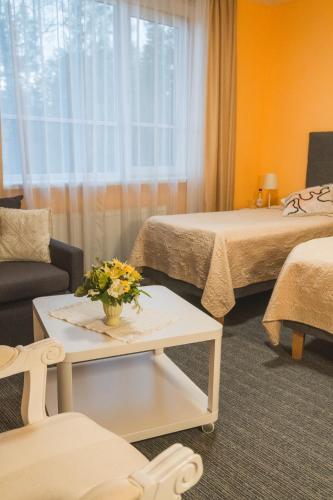 ein Hotelzimmer mit zwei Betten und einem Tisch mit Blumen in der Unterkunft Rēzijas in Ķegums