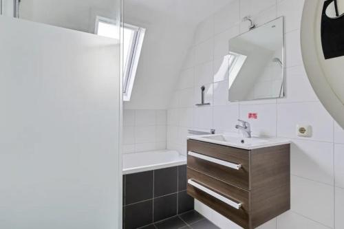 a bathroom with a sink and a tub and a mirror at Vijverzicht de Goudkarper 154 in Gramsbergen