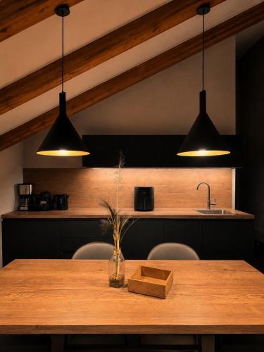 a kitchen with a wooden table and three lights at Residence Pranterhof in Marlengo