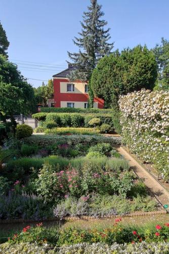 a garden with flowers and a red house in the background at Dom w ogrodzie in Puszczykowo