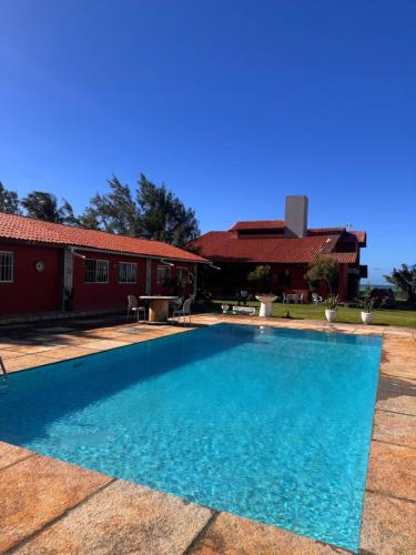 a large blue swimming pool in front of a red building at Suítes icarai vila in Caucaia