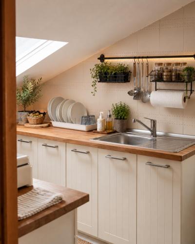 a kitchen with white cabinets and a sink at Appartamentino Mansardato in Pedara