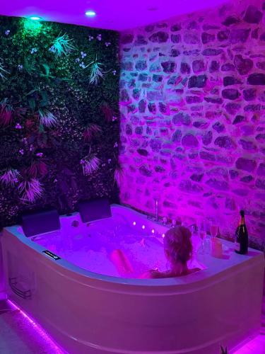 a woman in a hot tub with pink lights at Villa Romance Intime Prestige -Jacuzzi Privatif, , Table a massage , Fauteuil tantra, Balançoire romantique in Vienne